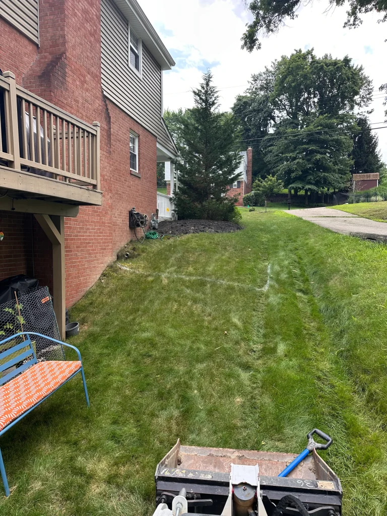 Retaining Wall Before Photo Showing Grassy Hill Next To Home